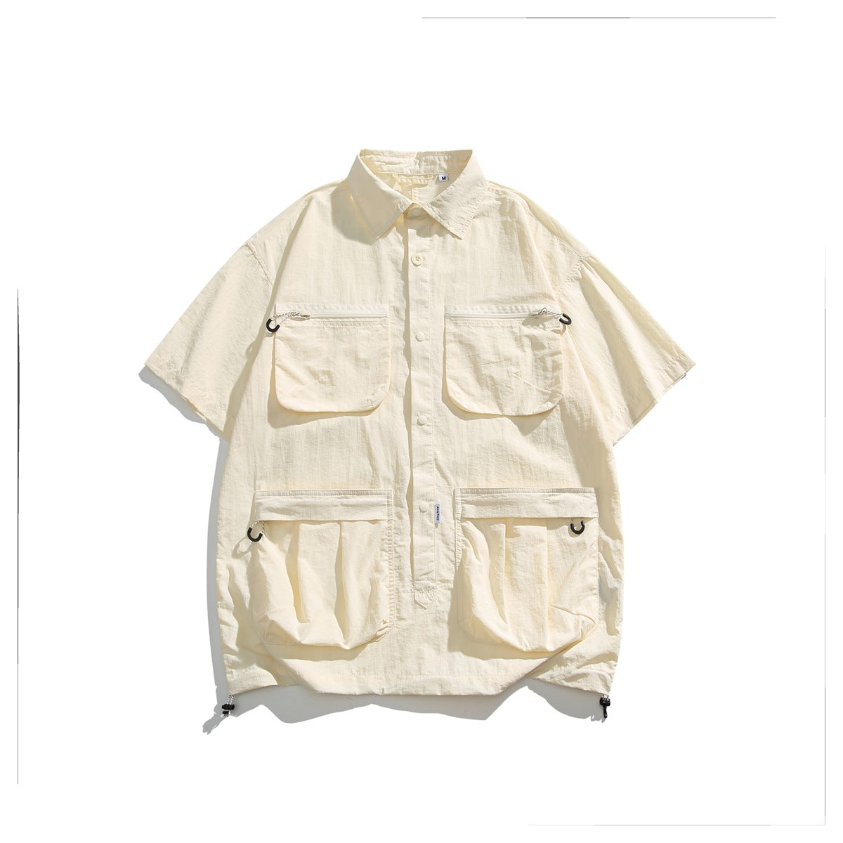 Sand cream short-sleeve utility shirt flat lay with four flap pockets and hem drawcords
