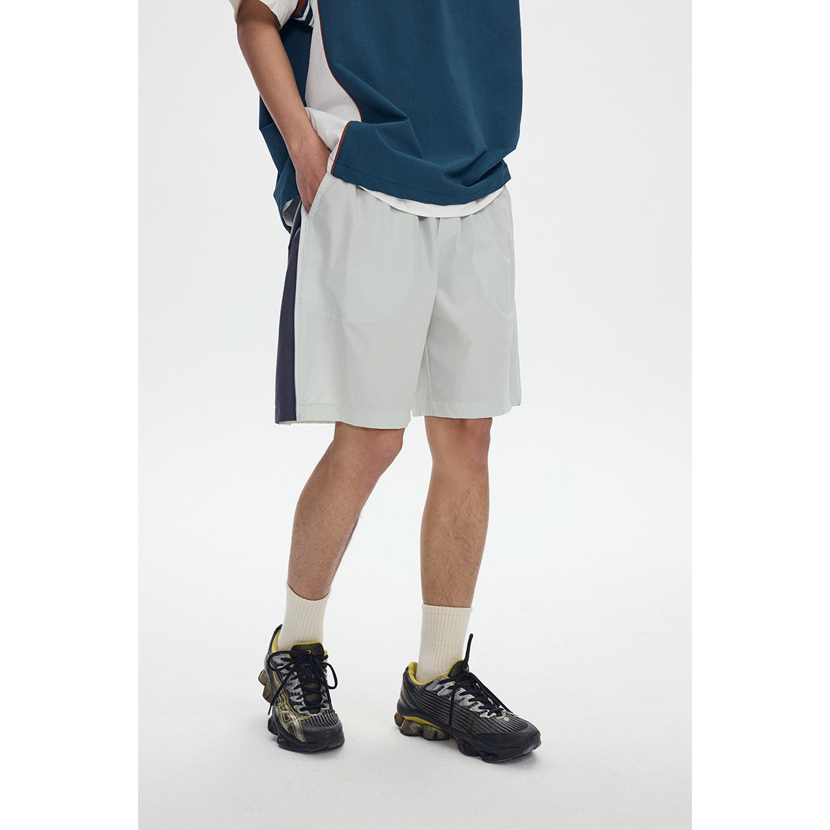 Close view of a model wearing white shorts with a dark side panel and a teal top.