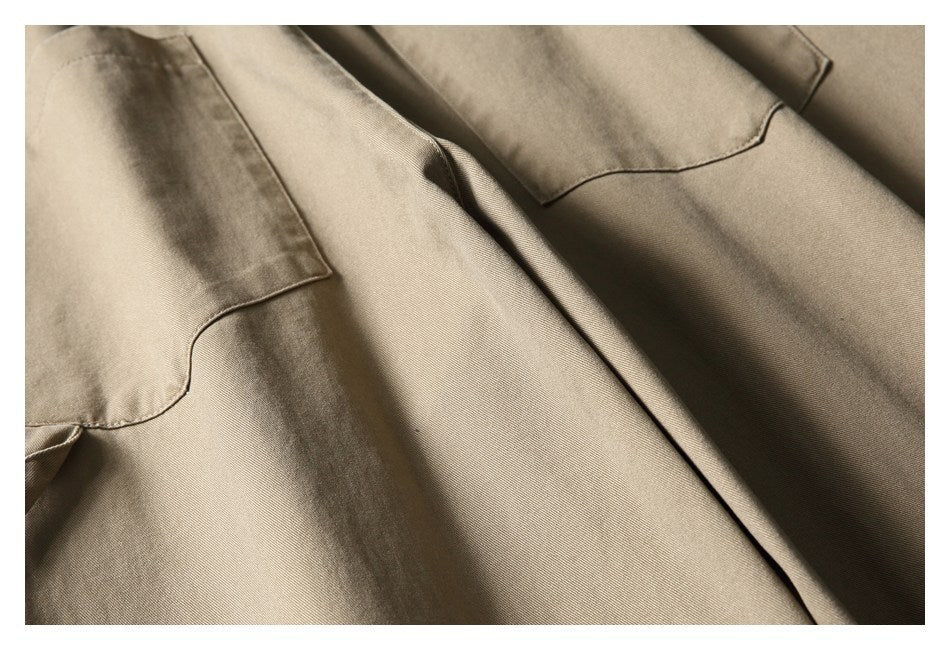 Close-up of taupe trousers showing large stitched patch pockets.