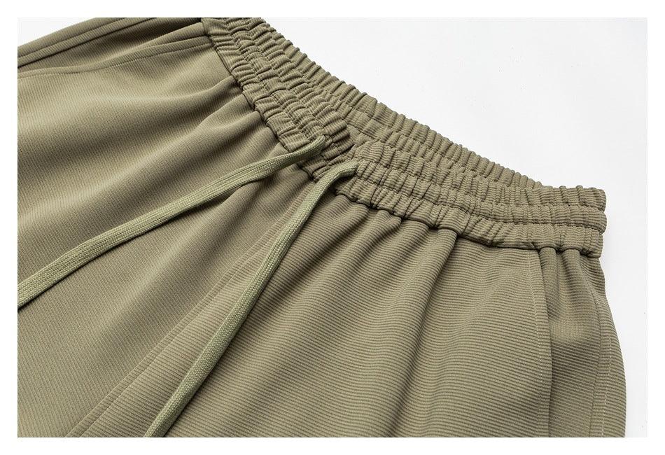 Close-up of olive-khaki pants showing the gathered waistband and drawstrings.