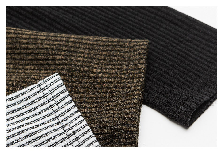 Close-up of black, brown, and white striped ribbed shirt fabric and stitching.