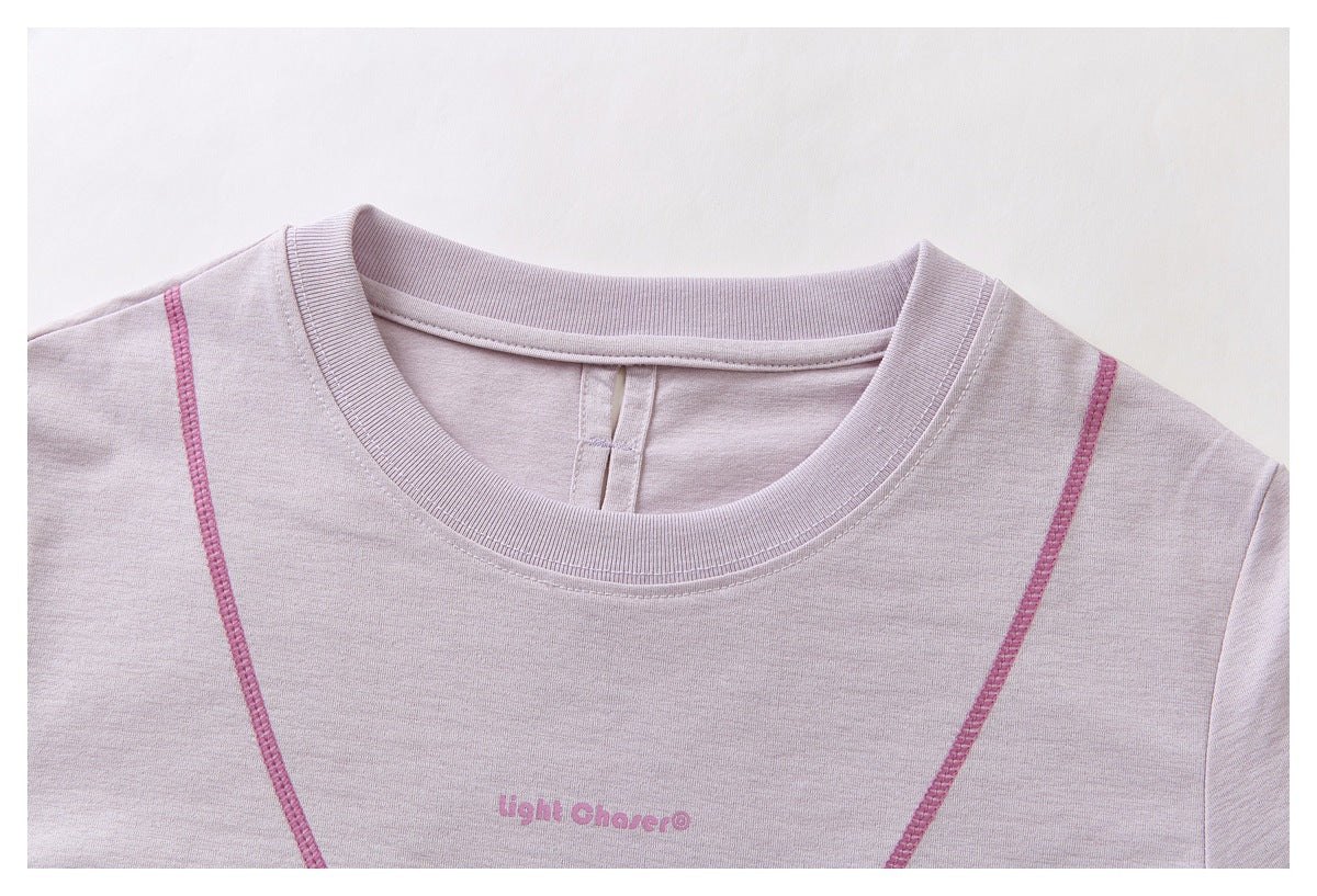 Close-up of a pale lavender crew neck top with pink contrast seams and small pink chest lettering.