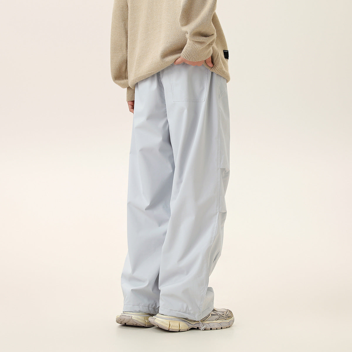 Rear view of a model wearing light gray wide-leg pants with a back pocket and panel seams.