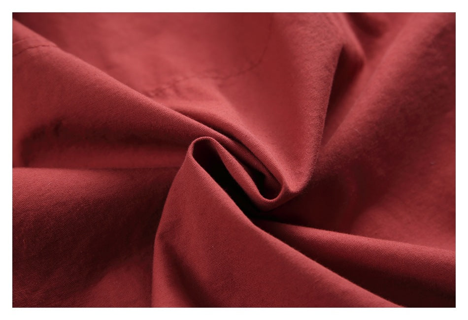 Close-up of muted red fabric draped into soft folds, showing its surface texture.