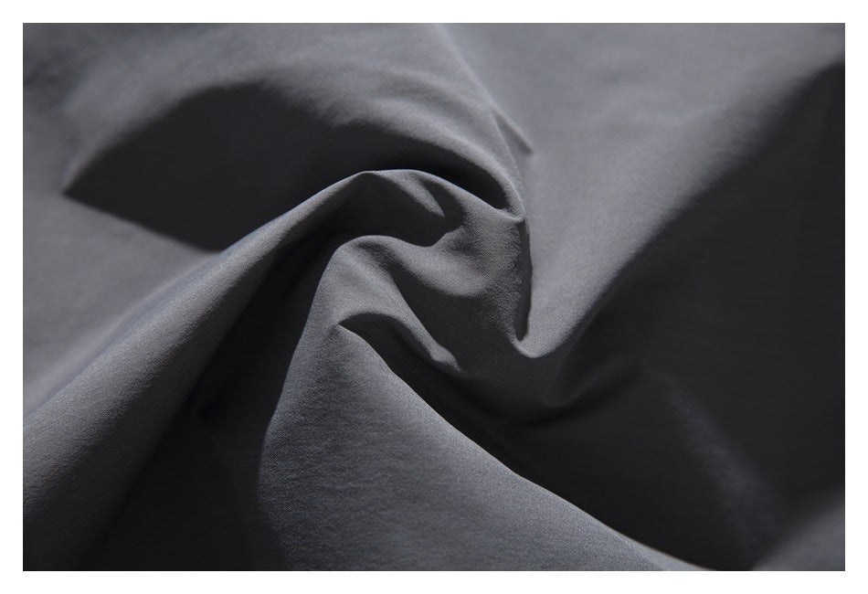 Close-up of dark charcoal fabric gathered into folds, showing its surface texture.