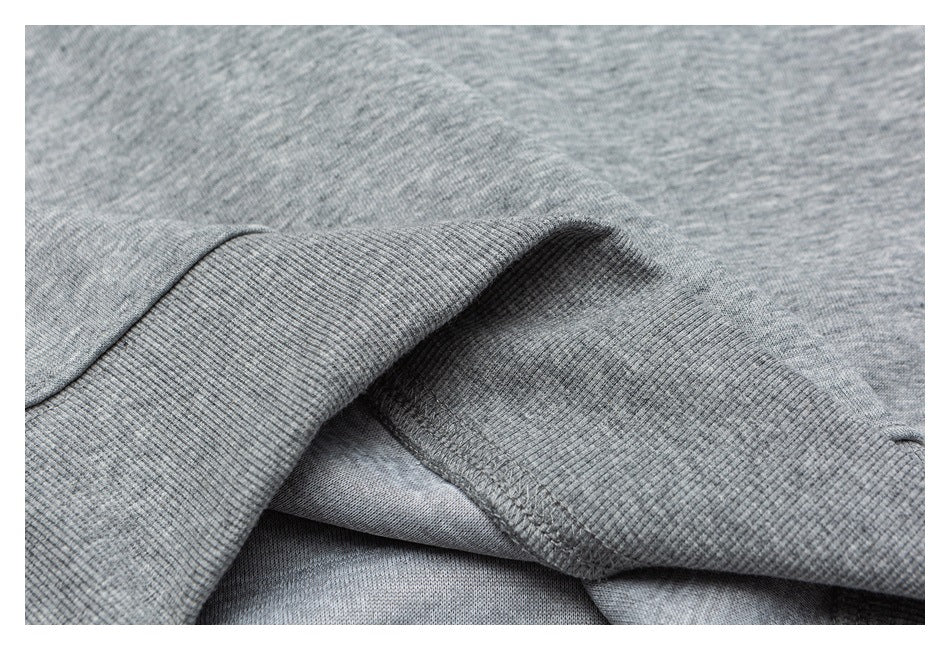 Close-up of gray heathered knit fabric showing a ribbed edge and stitched seam.