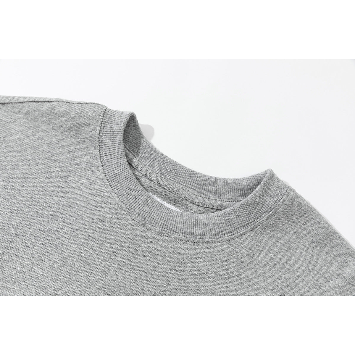 Close-up of a heather-gray crewneck shirt showing its ribbed collar and shoulder seam.