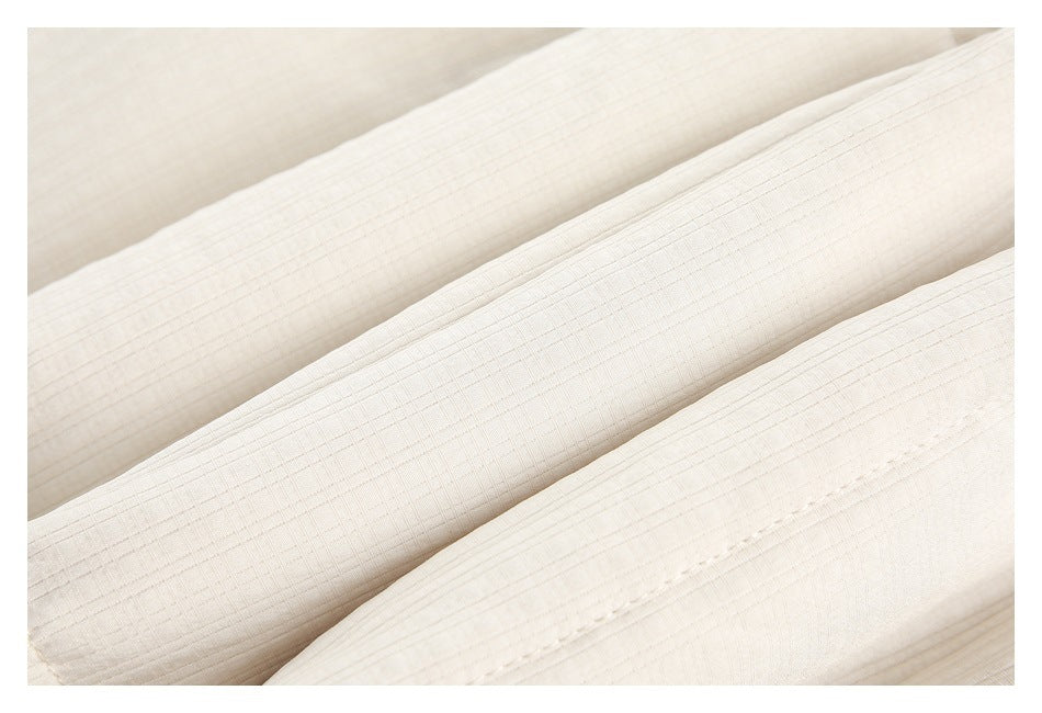 Close-up of ivory fabric arranged in folds, showing a subtle grid texture and stitching.
