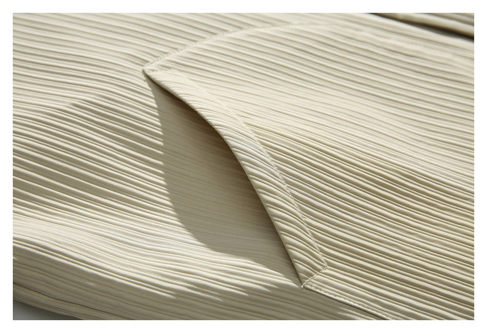 Close-up of an angled seam or pocket opening on an ivory garment with fine vertical pleats.