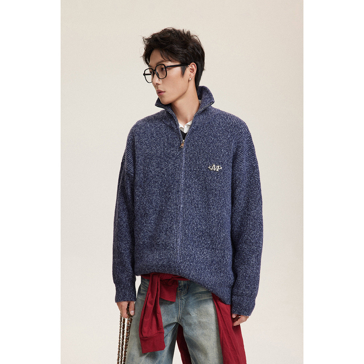 Closer view of a model wearing a navy ribbed zip-neck sweater with a raised collar and chest emblem.