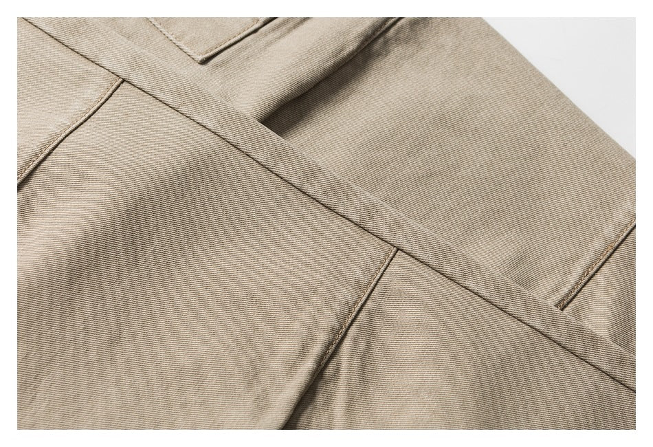 Close-up of beige twill trousers showing a pocket edge and intersecting stitched seams.