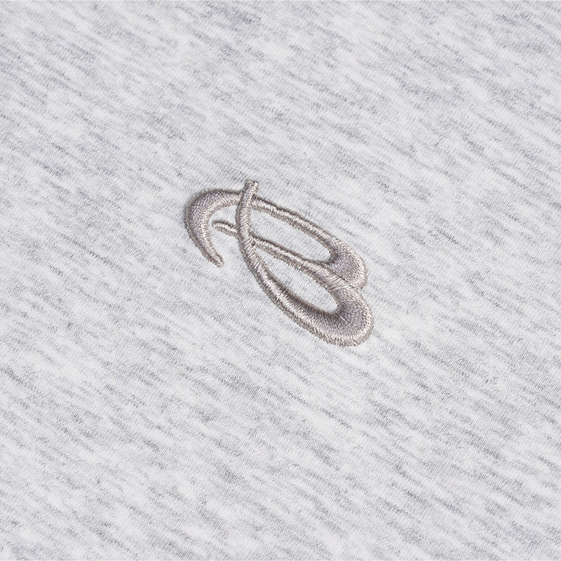 Close-up of a small embroidered abstract mark on heather gray T-shirt fabric.