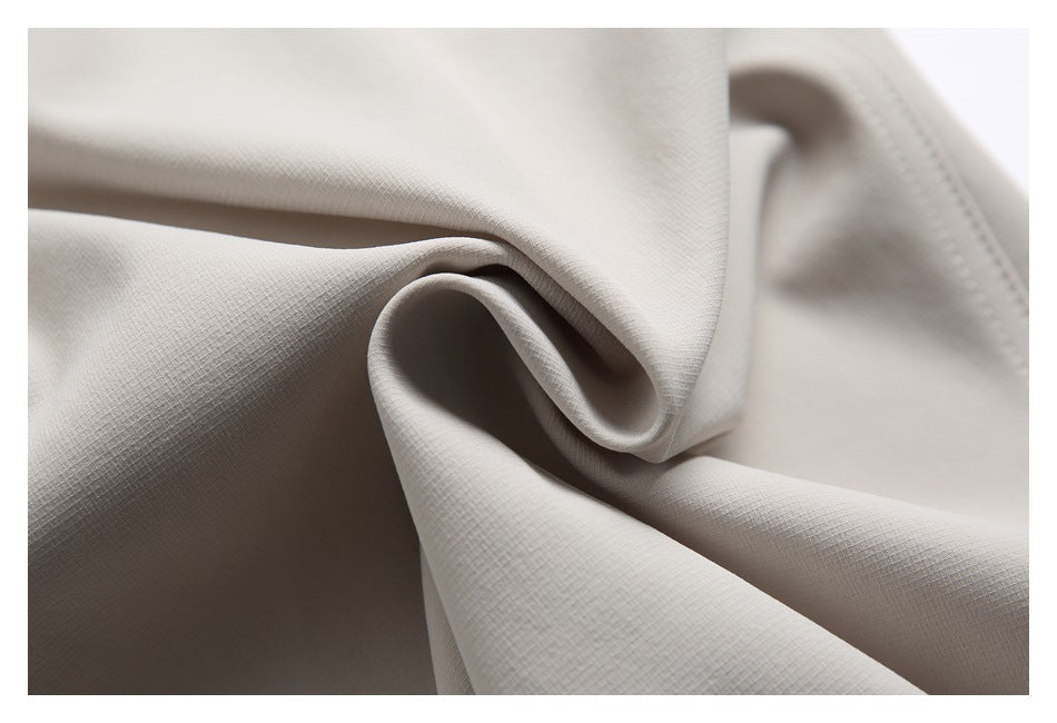 Close-up of light beige garment fabric folded to show its subtle surface texture.