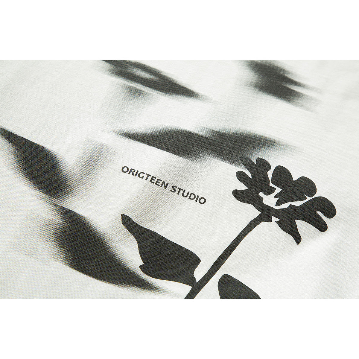 Close-up of an off-white T-shirt with a black flower graphic and small English lettering.