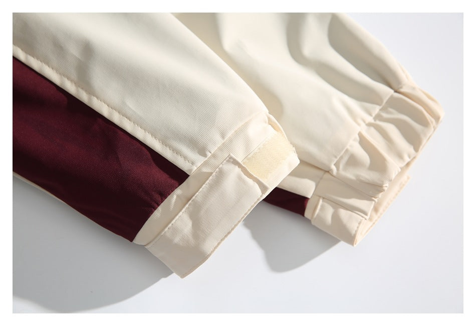 Close-up of cream garment cuffs with burgundy panels and stitched seams.