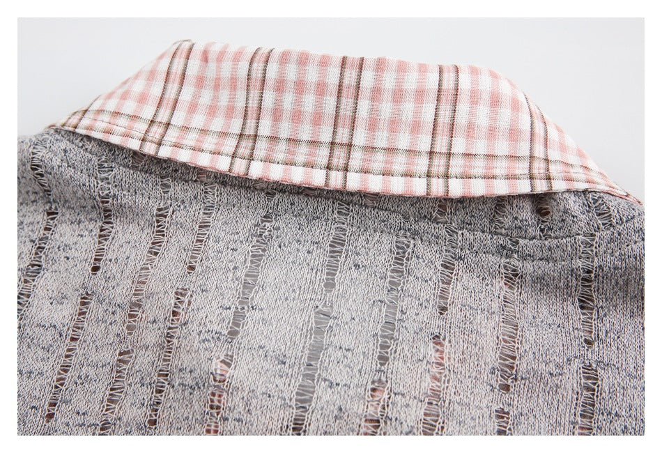 Upper back of a gray distressed open-knit sweater with a pink-and-white plaid collar.