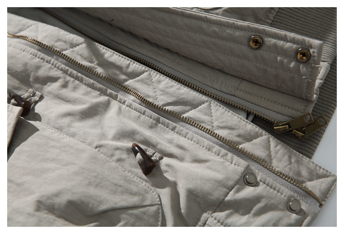 Close-up of a gray jacket front with a zipper, snap-fastened placket, and toggle closures.