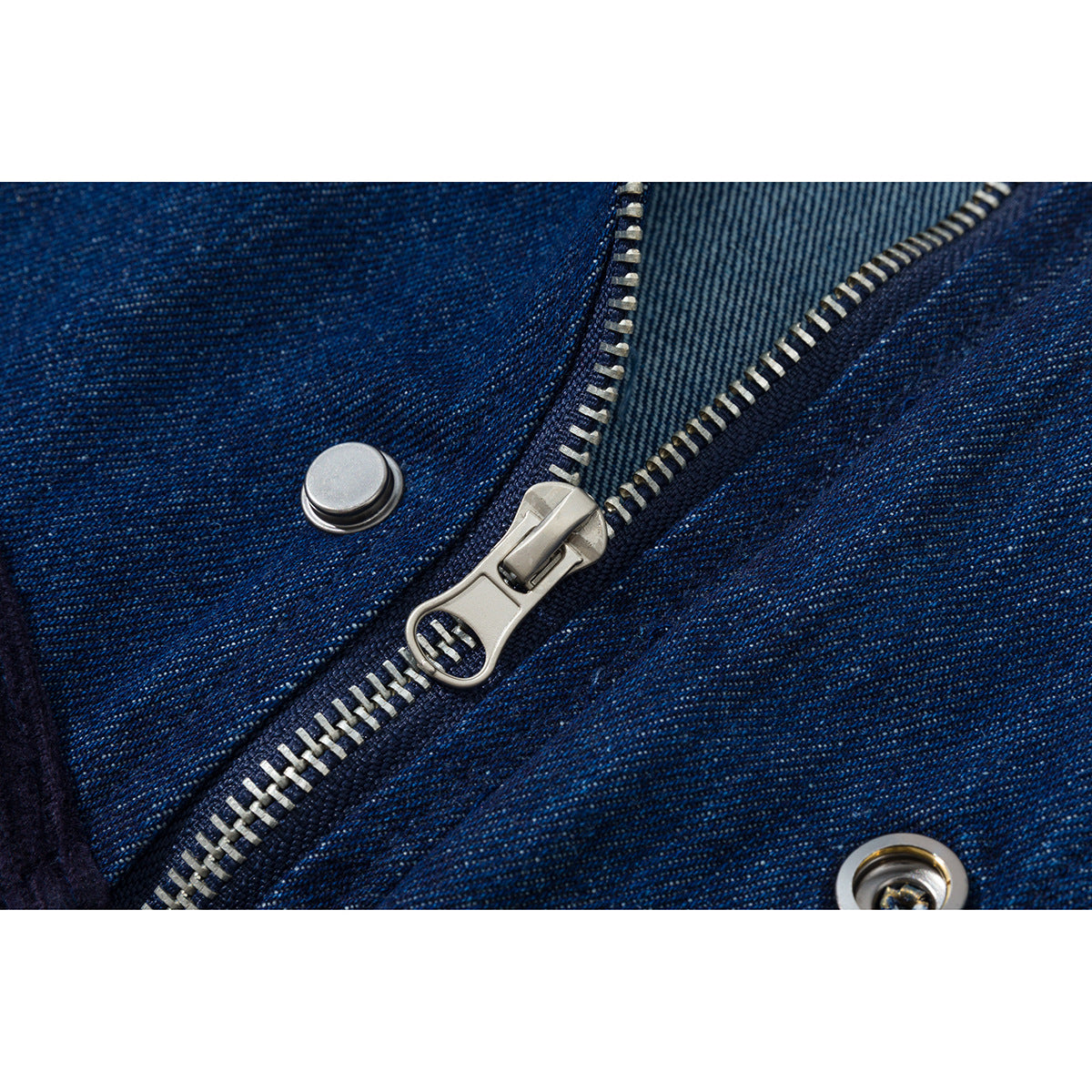Close-up of a dark blue jacket's metal zipper, snap, and denim-like surface texture.