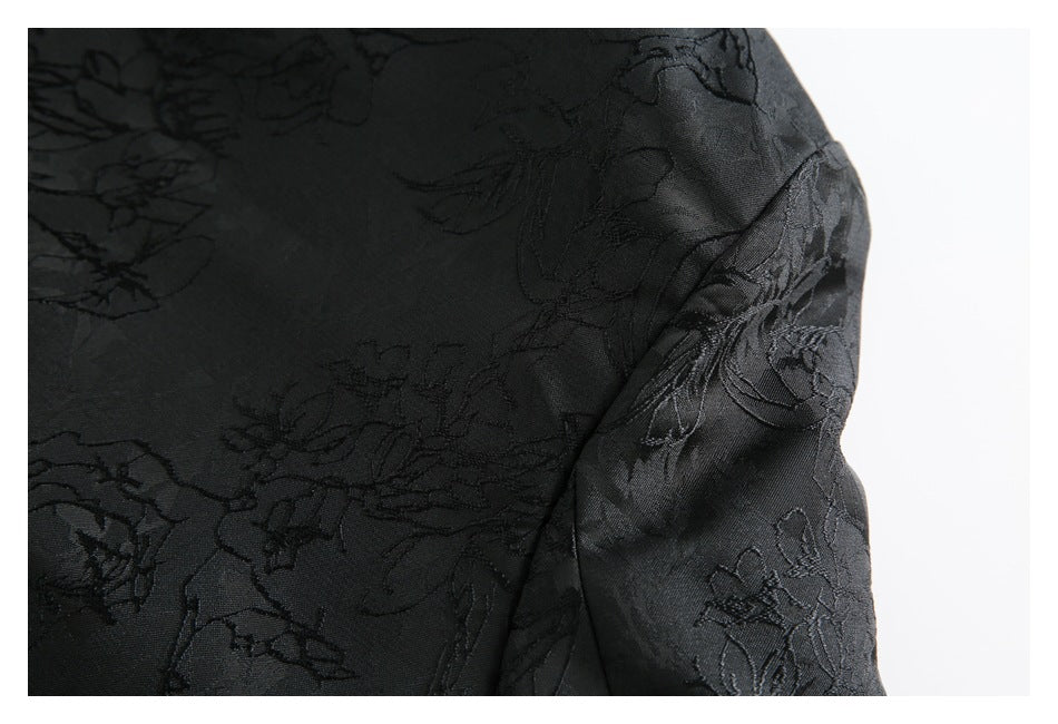 Close-up of black fabric with a subtle raised floral pattern and a curved seam.