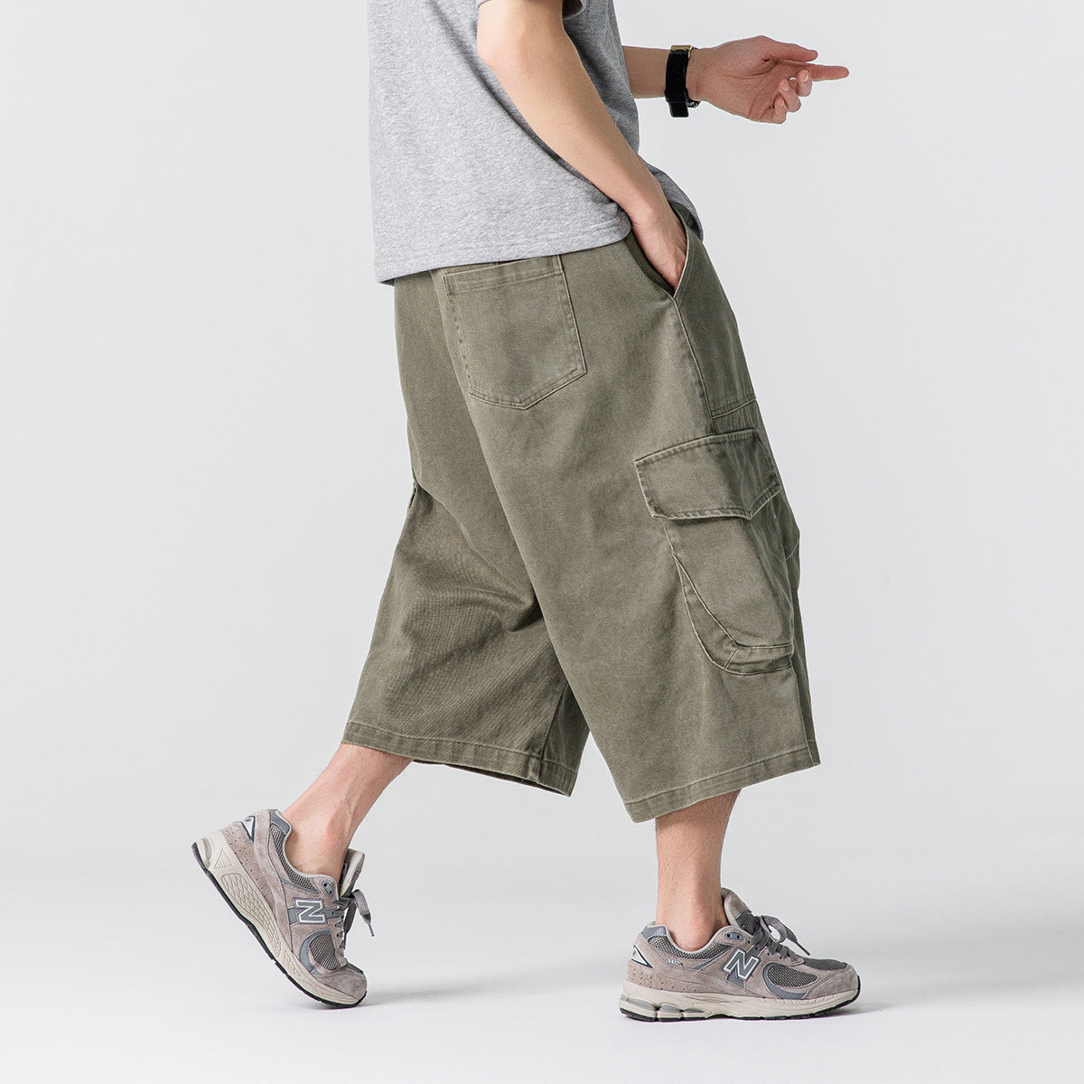 Side view of a model wearing loose olive cargo shorts, showing the rear pocket and large flap cargo pocket.