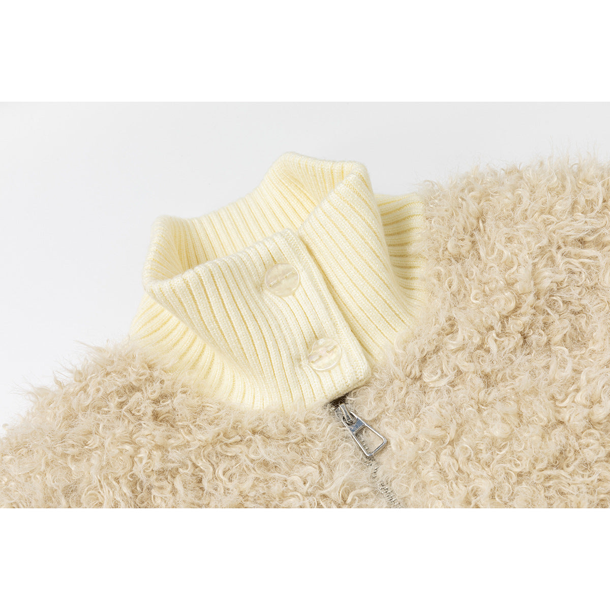Close-up of the ivory ribbed high collar, two buttons, shaggy beige panel and silver zipper pull.