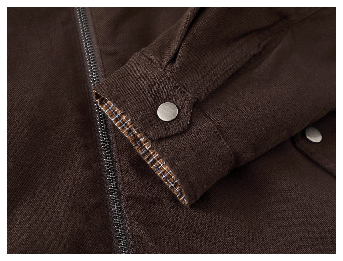 Close-up of a dark brown jacket cuff with a silver snap, checked lining, and zipper nearby.