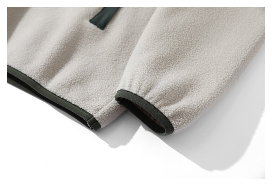 Close-up of a light beige fleece sleeve cuff with dark green trim.