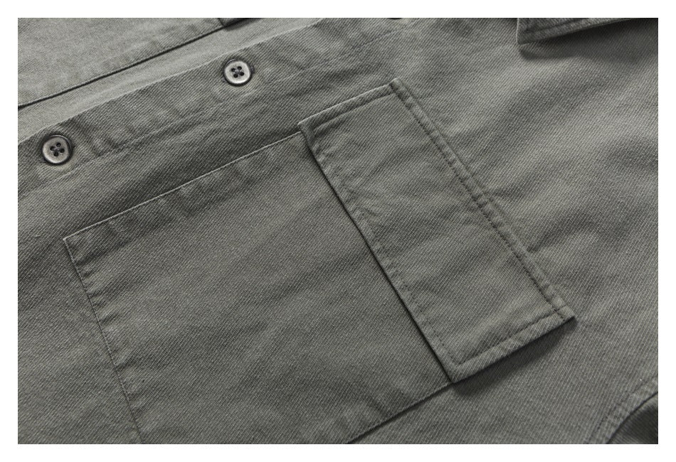 Close-up of a charcoal gray shirt’s button placket and rectangular chest pocket.