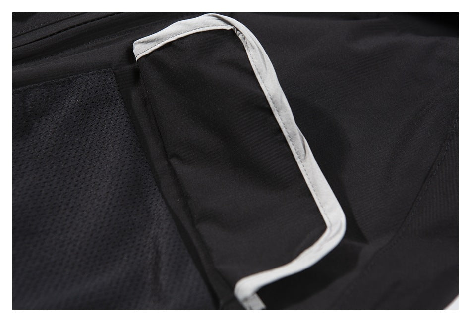 Close-up of a black garment pocket with light-colored piping and adjacent mesh fabric.