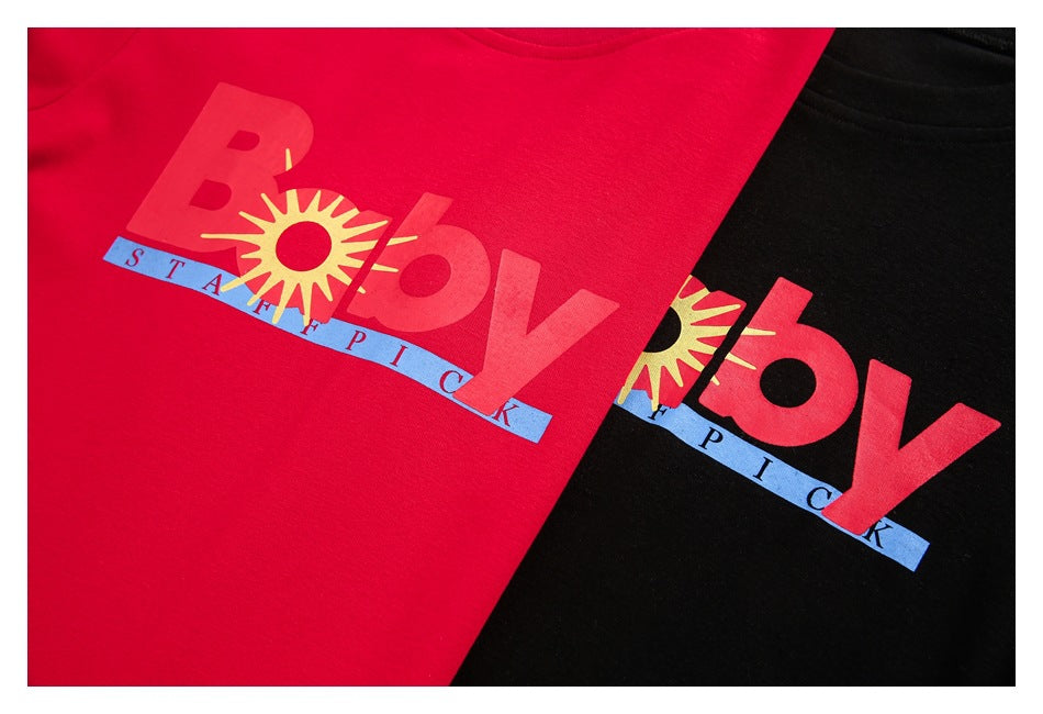 Close-up of red and black T-shirts with matching colorful sun-and-lettering chest graphics.