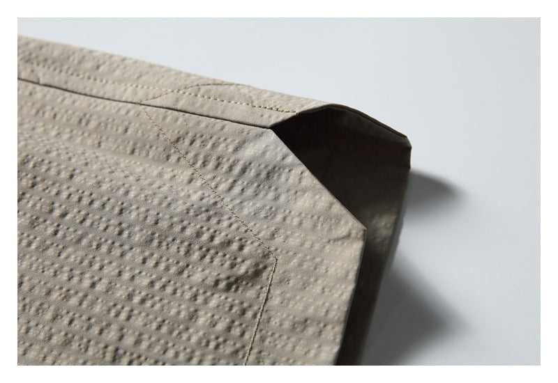 Close-up of a folded, stitched edge on taupe shorts, highlighting the raised dotted texture.