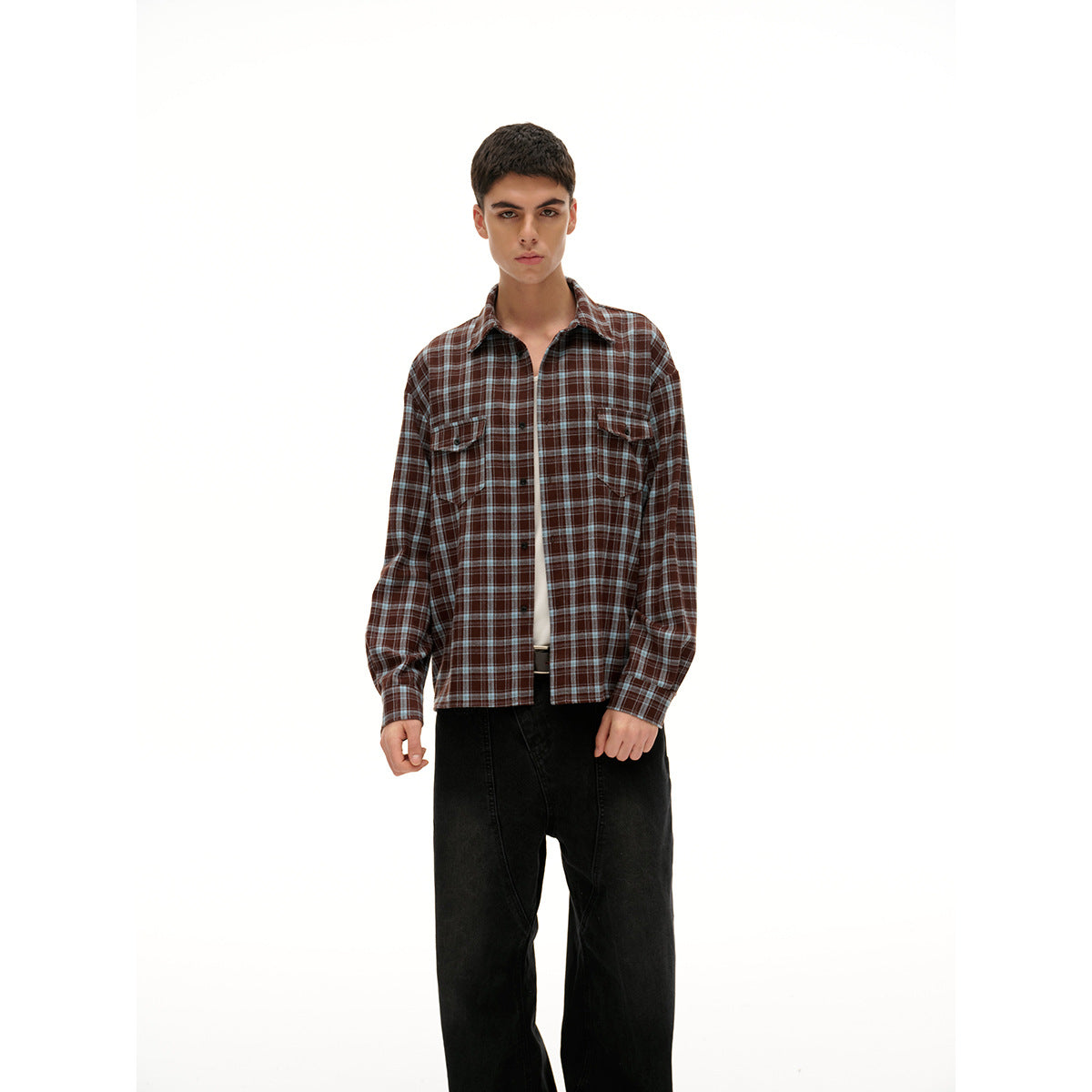 Front view of a model wearing a brown and dark plaid button-up shirt with two chest pockets over a white tee.