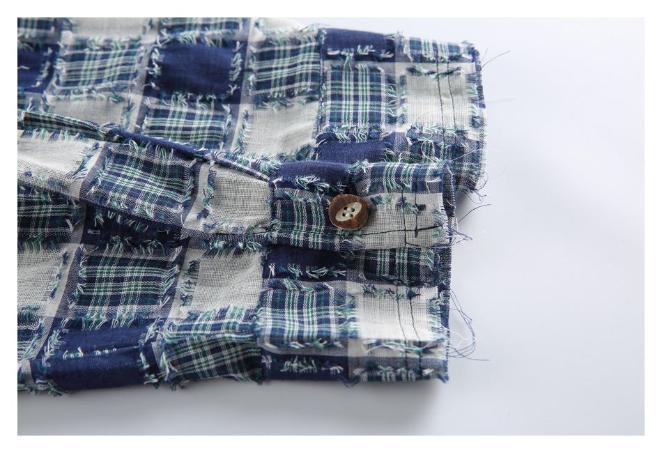 Close-up of a buttoned cuff on the frayed blue, green and white patchwork plaid garment.