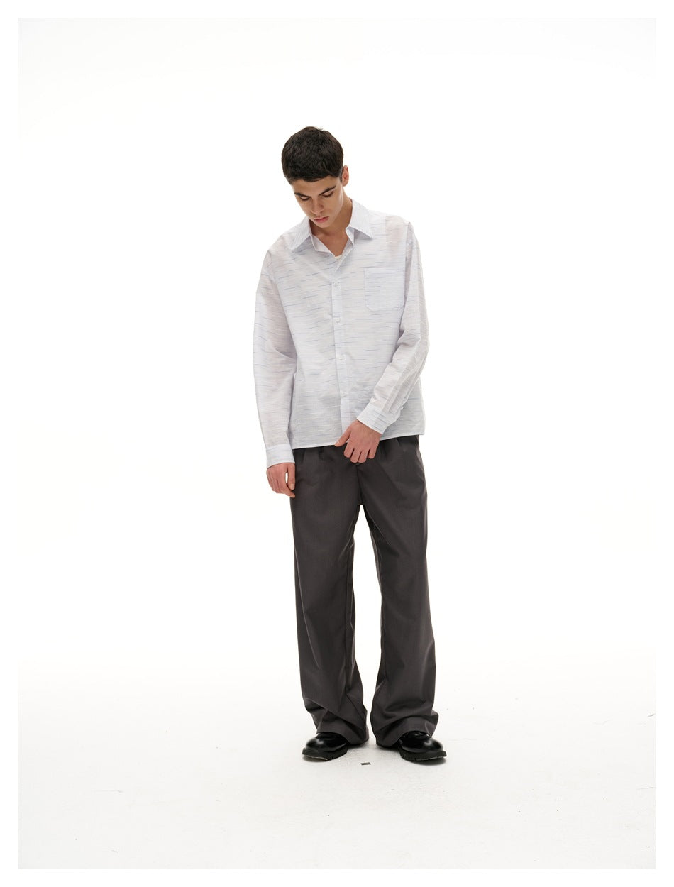Full-length model wearing a white button-up shirt with subtle blue-gray dashes and loose charcoal trousers.