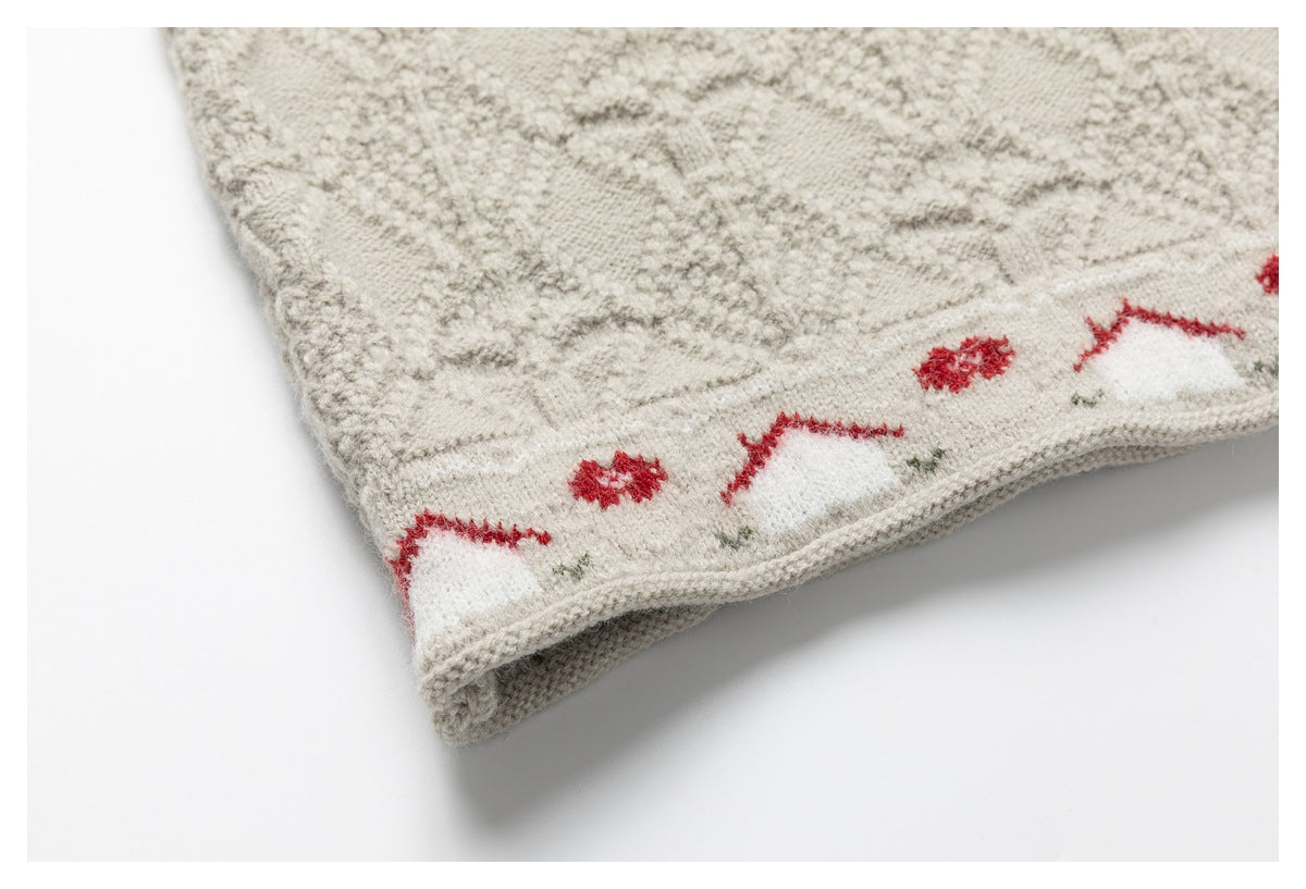 Close-up of the cream sweater's patterned ribbed hem, with red and green motifs and a folded edge.
