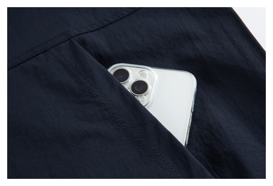 Close-up of a dark navy garment pocket holding a white smartphone.