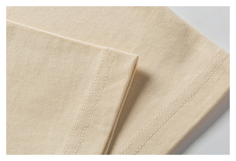 Close-up of the beige T-shirt’s stitched sleeve and hem seams.