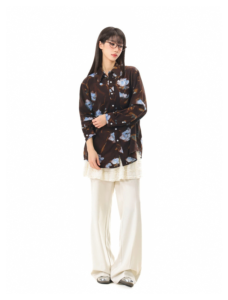 Full-length angled view of a model wearing a dark brown floral button-up shirt over cream layers.