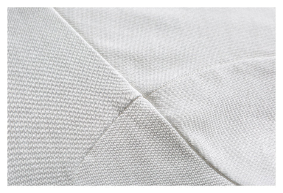 Close-up of intersecting stitched seams on white fabric.