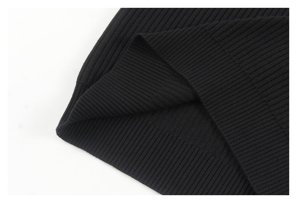 Close-up of black ribbed garment fabric folded to show its thick ribbed edge.