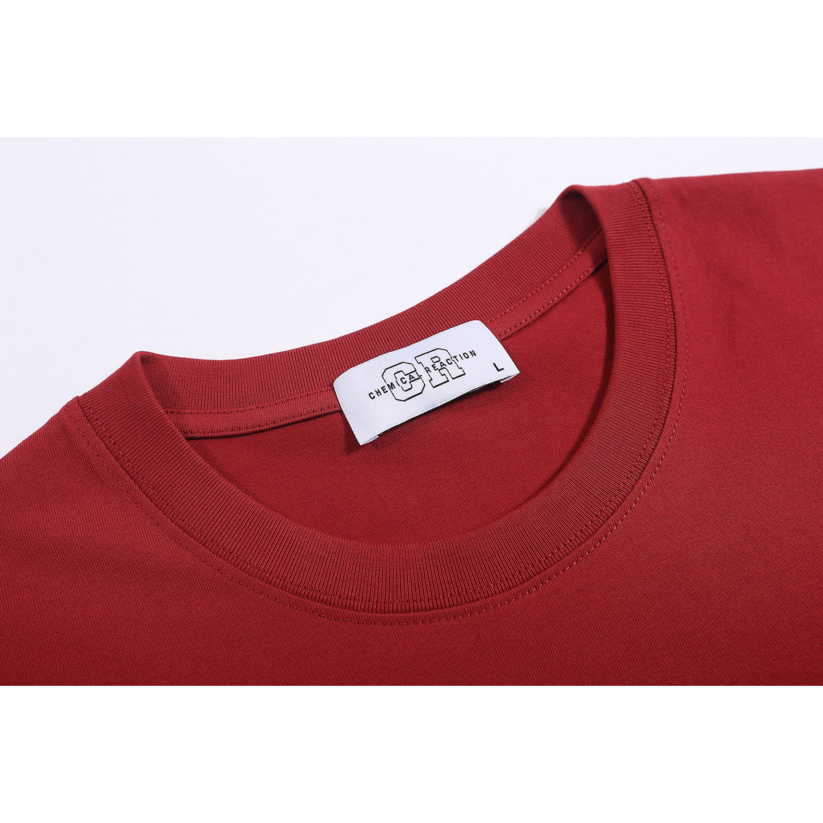 Close-up of the red T-shirt's ribbed crew neck and inner brand and size label.