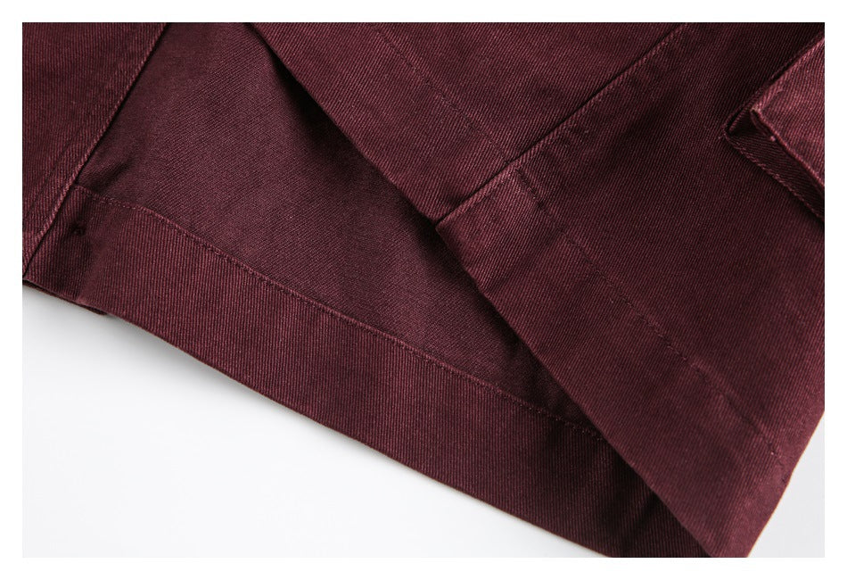 Close-up of burgundy garment fabric with a stitched hem and overlapping seam.