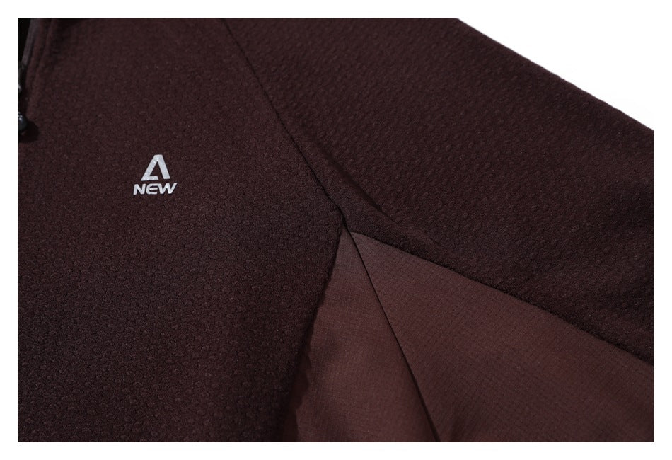 Close-up of a burgundy jacket showing its small chest logo, textured panels, and smooth side insert.