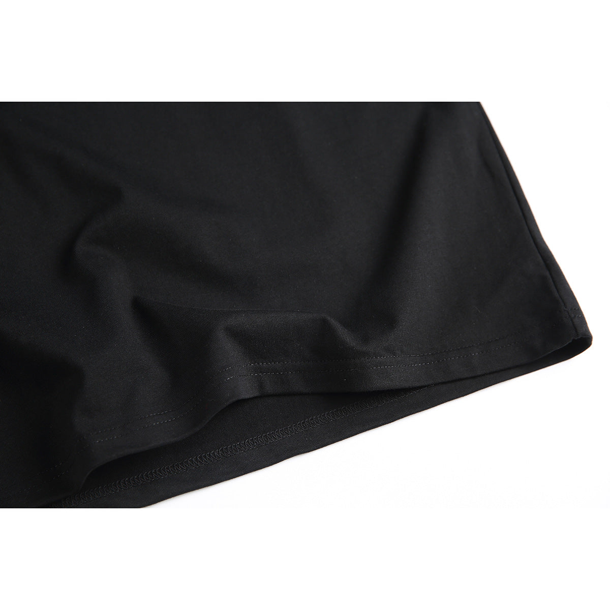 Close-up of the black T-shirt’s plain fabric and double-stitched bottom hem.