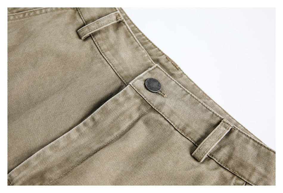 Close-up of taupe trousers showing a dark waistband button, belt loops, and fly stitching.