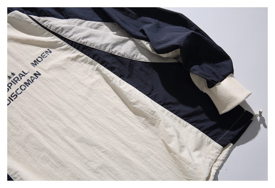 Close-up of an ivory and navy color-block pullover with printed lettering and a ribbed ivory cuff.