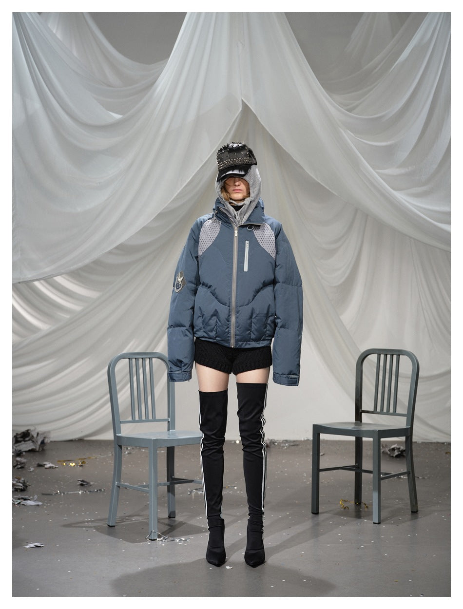 Model wearing a blue puffer jacket with gray knit hood, studded cap, knit shorts and black thigh-high boots
