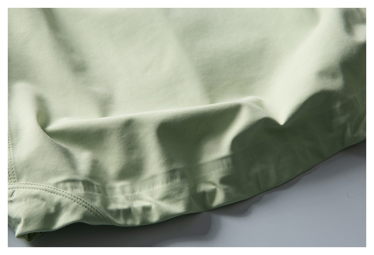Close-up of the pale green garment's folded lower hem and stitching.