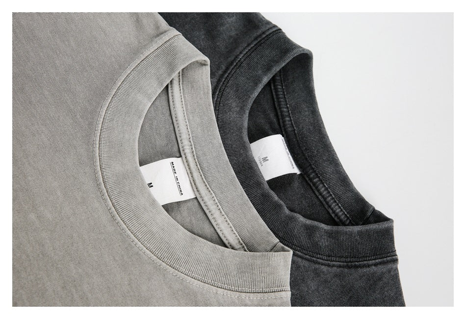 Close-up of the necklines and inner size labels of light gray and charcoal washed T-shirts.