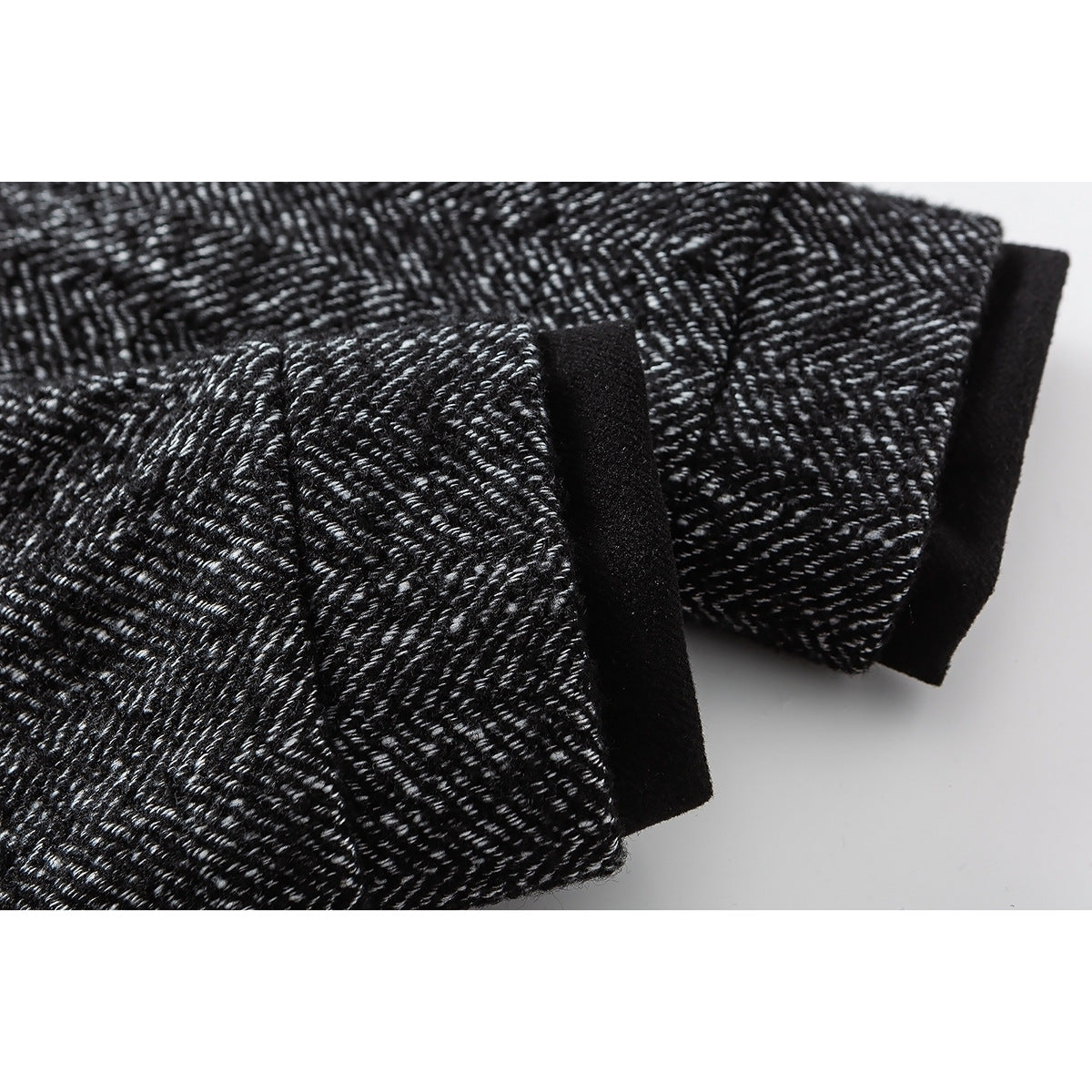 Close-up of the black-and-white herringbone jacket sleeve with a black cuff edge.